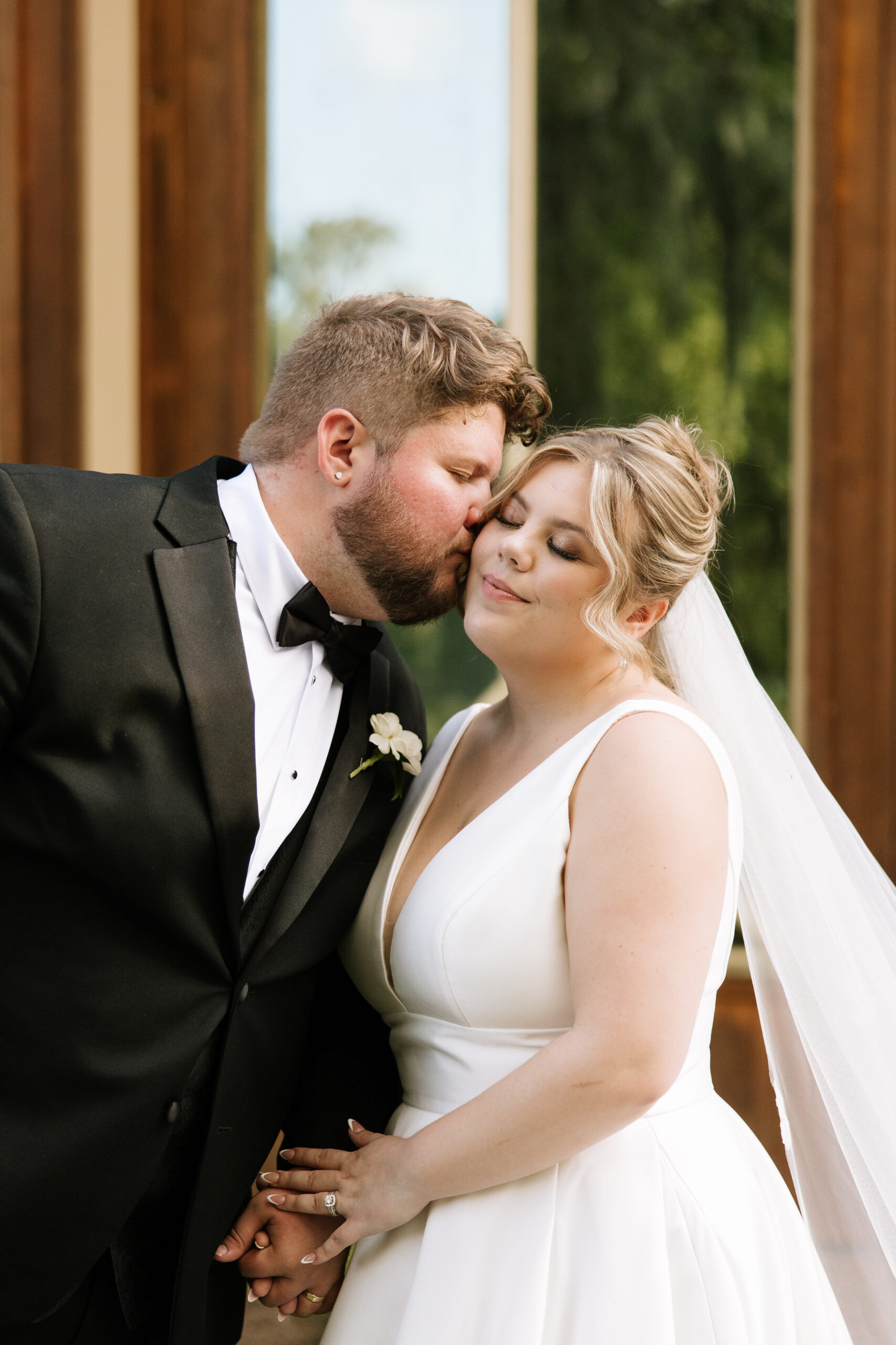 bride and groom holding hands groom kissing bride on the cheek